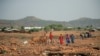 FILE - Residents walk past Adi Harush Refugee camp in Mai Tsberi town in Tigray Region, Ethiopia, June 26, 2021.