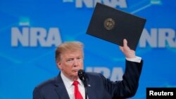 US President Donald Trump holds up an executive order as he announces the United States will drop out of the Arms Trade Treaty during a speech at the National Rifle Association-Institute for Legislative Action's148th annual meeting in Indianapolis, Indiana, U.S., April 26, 2019.