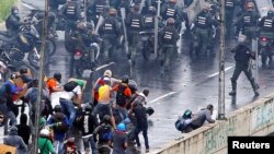 En esta foto de archivo se ve a un miembro de las fuerzas anti disturbios (derecha) apunta lo que parece ser una pistola hacia una multitud de manifestantes durante una protesta contra el gobierno del presidente venezolano, Nicolás Maduro, en Caracas, el 19 de junio de 2017.