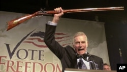 FILE - In this Monday, Oct. 21, 2002 file photo, National Rifle Association President Charlton Heston holds up a rifle as he addresses gun owners during a "get-out-the-vote" rally in Manchester, N.H.
