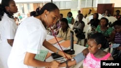 A nurse inspects a pregnant woman outside a ward at a maternity hospital in Obio district in Nigeria's oil city of Port Harcourt, March 24, 2011.
