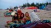 FILE - Afghan children are covered with a blanket as their families camp outside the Directorate of Disaster, in Herat, Afghanistan, Nov. 29, 2021.
