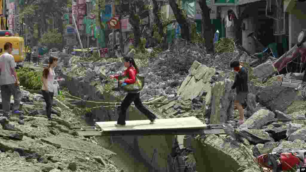A woman crosses over a trench made from a massive gas explosion in Kaohsiung, Taiwan, Aug. 1, 2014. 