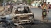 A man rides bicycle past a destroyed car on a road following ethnic unrest between Buddhists and Muslims in Meikhtila, March 23, 2013.