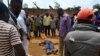 FILE - Civilians gather to look at the dead body of an unidentified man killed during fighting between the army and militia fighters in Beni, eastern Democratic Republic of the Congo, June 22, 2017.