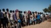 FILE - Ethiopian refugees who fled the Ethiopia's Tigray conflict wait in a line for the food distribution at the Um Rakuba refugee camp in Sudan's eastern Gedaref state, Dec. 12, 2020.