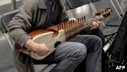 FILE - A musician checks his sarangi in a Barcelona subway station, Nov. 27, 2015.