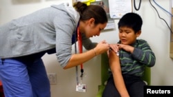 A boy gets an influenza vaccine injection at a health care clinic, in Boston, Massachusetts, in this January 12, 2013, file photo.