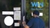 FILE - A man is handed an unemployment benefit application form by a security guard from behind glass doors of a state WIN Job Center in north Jackson, Mississippi, April 2, 2020. 