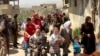 This photo, released by the Syrian official news agency SANA, shows civilians carrying their belongings leaving towns and villages, in the eastern Ghouta region near Damascus, Syria, March. 25, 2018. 