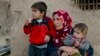 FILE - Members of a Syrian Kurdish refugee family from Kobani sit in the village of Alanyurt on the Turkish side of the Turkey-Syria border.