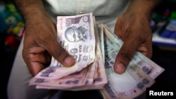 A private money trader counts Indian rupee currency notes at a shop in Mumbai, India, Aug. 1, 2013. 