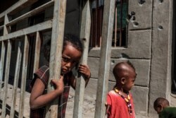 FILE - Children play in front of a bullet-damaged wall of a destroyed store in the village of Bisober, in Ethiopia's Tigray Region, Dec. 9, 2020.