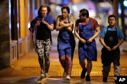 Personas en el área de uno de los ataques del sábado por la noche en Londres salen de la zona de cordon policial.
