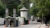 FILE - A policeman (2nd R) and private security personnel stand guard at the entrance of a road leading towards the U.S. consulate in Lahore.