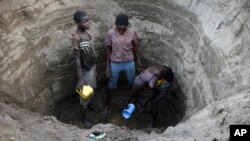 In this photo taken March 22, 2019, Kenyan children dig deep into a dry river bed to retrieve water in Tarach, Turkana county, in northern Kenya.