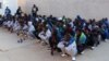 FILE - Migrants wait before being deported by Libyan authorities, in Misrata, Libya, Feb. 19, 2018.