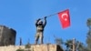 FILE - A soldier waves a Turkish flag as Turkish troops secure Bursayah Hill, which separates the Kurdish-held enclave of Afrin from the Turkey-controlled town of Azaz, Syria, Jan. 28, 2018. 