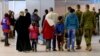 FILE - Syrian refugees wait at Marka Airport in Amman, Jordan, to complete their migration procedures to Canada, Dec. 8, 2015.