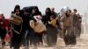 FILE - People walk with their belongings as they flee the rebel-held town of Hammouriyeh, eastern Ghouta, Syria, March 15, 2018. 
