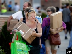 Personas en Wilmington, Carolina del Norte, reciben cajas con alimentos de emergencia, agua y carpas en un centro de distribución de ayuda, el martes 18 de septiembre de 2018.