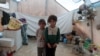FILE - Syrian siblings, displaced from eastern Idlib province, pose for a picture in a tent at Atmeh camp in Syria, near the Turkish border, June 19, 2020. 