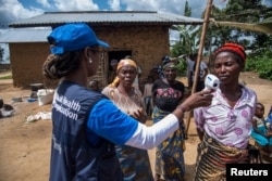 La doctora Marie-Roseline Darnycka Bélizaire, de la Organización Mundial de la Salu, habla con mujeres como parte de la estrategia para detectar posibles contactos de personas infectadas con ébola en Mangina, en la República Democrática del Congo, el 26 de agosto de 2018.