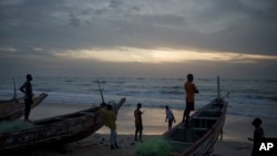Jóvenes senegaleses se reúnen al atardecer alrededor de piraguas en la playa en Fass Boye, Senegal, el martes 29 de agosto de 2023