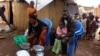 A family of refugees from the Democratic Republic of Congo sit by their makeshift hut at the Kenani refugee transit camp in Nchelenge, Oct. 30, 2017, during a visit by Zambian President Edward Lungu.
