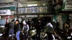 La gente se reúne frente al centro comercial en Bagdad, Irak, donde hombres armados atacaron el lunes, 11 de enero, de 2016, después de hacer estallar un coche bomba.