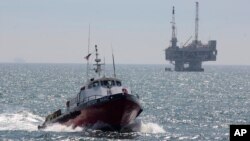 FILE - A service boat carries workers back to shore from a platform off Seal Beach, California, May 16, 2015. 