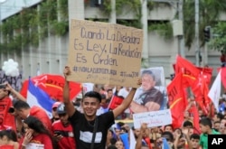 An opposition supporter carries a sign with a message that reads in Spanish: "When dictatorship is the law, revolution is an order," during an opposition protest in support of Salvador Nasralla, in San Pedro Sula, Honduras, Jan. 6, 2018.