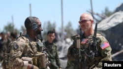 FILE - U.S. forces are seen at the Kurdish People's Protection Units (YPG) headquarters after it was hit by Turkish airstrikes in Mount Karachok near Malikiya, Syria, April 25, 2017.