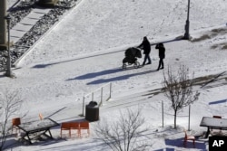 Personas pasean en a nieve en la Plaza Barney Allis, en Kansas City, Missouri, el sábado 19 de enero de 2019.