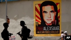 Peatones caminan cerca de un cartel pidiendo la libertad del empresario colombiano y enviado especial venezolano Alex Saab, en Caracas. Septiembre 9, 2021.