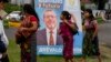 Varias personas pasan frente a un cartel electoral del candidato Bernardo Arévalo, quien encabeza las encuestas para la segunda vuelta de elecciones presidenciales en Guatemala, el 15 de agosto de 2023.