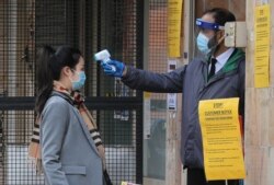 A security guard takes the temperature of a customer wanting to enter an Asian supermarket in the Chinatown district of London on May 13, 2020.