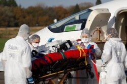 Personal médico baja un paciente de un avión durante una operación de traslado de personas que padecen la enfermedad del coronavirus (COVID-19), en el aeropuerto de Vannes, Francia, el 2 de noviembre de 2020.