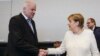 German Chancellor Angela Merkel, right, shakes hands with Interior Minister Horst Seehofer, left, as they arrive for a special faction meeting of the Christian Union parties, ahead of a debate at the German parliament in Berlin, July 3, 2018.