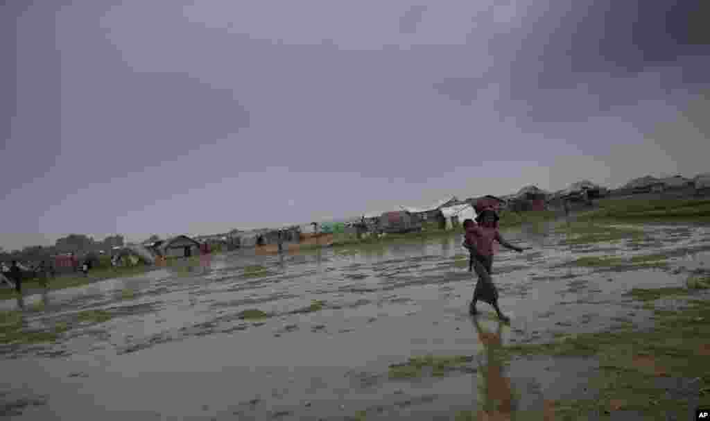 An internally displaced Rohingya woman walks carrying a sibling in a makeshift camp in Sittwe, Burma, May 14, 2013.