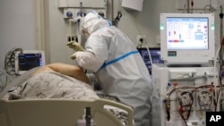 Un miembro del personal médico que usa un traje especial para protegerse contra el COVID-19 trata a un paciente con coronavirus en una UCI en el Hospital Clínico Regional 1, en Krasnodar, sur de Rusia, el 2 de noviembre de 2021.