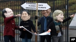 Activistas protestan sobre el rol de los líderes mundiales y los representan (presidente francés Hollande, primer ministro japonés Shinzo Abe, presidente Obama y Angela Merkel) en encontrar una manera para enfrentar el calentamiento global frente de las instalaciones donde se desarrolló la conferencia de la ONU, en Varsovia.