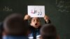 FILE - A Syrian refugee boy holds up a placard in Arabic, during class at a remedial education center run by Relief International in the Zaatari Refugee Camp, near Mafraq, Jordan, Jan. 21, 2016.