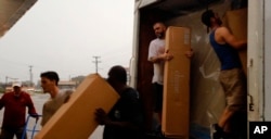 Trabajadores de una tienda de muebles suben cartones en un camión para salvar algunas piezas de una posible inundación causada por el río Cape Fear que esta a una milla (1,5 km) de la tienda. Fayetteville, Carolina del Norte. 15 de septiembre de 2018.