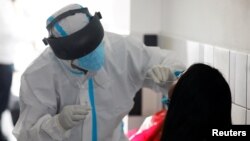 Un trabajador médico toma una muestra de hisopado nasal de un migrante guatemalteco deportado de EE.UU. para ser examinado por la enfermedad del coronavirus (COVID-19), en el Aeropuerto Internacional La Aurora, Guatemala, 6 de enero de 2021.
