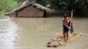 FILE - Flood affected boys move on a banana raft near partially submerged houses in Morigaon district east of Gauhati, Assam, India, Aug. 15, 2017.