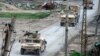 Vehicles belonging to the US-led coalition drive down a street in the front line Syrian village of Baghuz, Feb. 17, 2019. 