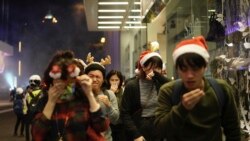 Residentes de Hong Kong celebrando la navidad reaccionan a los gases lacrimógenos lanzados por la policía la noche del 24 de diciembre de 2019.