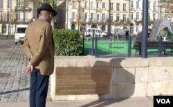 Karfa Diallo reads a plaque installed as a memorial to Bordeaux's slave-trading past. (L. Bryant/VOA)