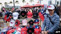 2024年1月7日，总统大选前一周，高雄，一名街头小贩在主要反对党国民党的竞选集会上出售旗帜和帽子。（法新社）